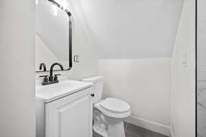 Bathroom with lofted ceiling, vanity, and dark tile patterned floors