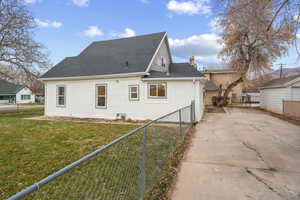 Rear view of house with driveway, a shingled roof, and a chimney