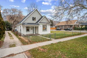 Bungalow-style house with covered porch, a fenced front yard, a gate, and roof with shingles