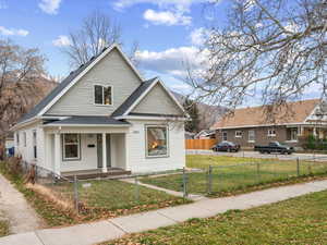 Bungalow-style house with covered porch, a fenced front yard, a gate, and roof with shingles