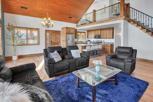 Living area featuring suspended lighting, a vaulted wooden ceiling, and light wood-type flooring