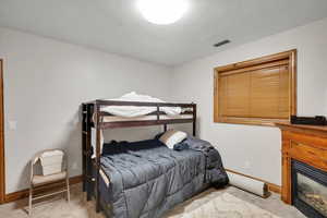 Bedroom featuring light carpet and a glass covered fireplace