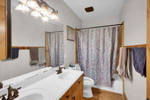 Full bath with double vanity, shower / bath combo, and light tile patterned floors