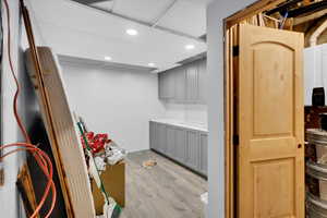 Laundry area with a drop ceiling, light wood-style floors, water heater, and recessed lighting