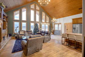 Living area with a chandelier, high vaulted ceiling, wood ceiling, and light wood finished floors