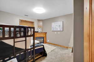 Carpeted bedroom featuring baseboards and a glass covered fireplace