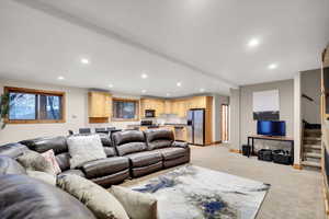 Living room with stairs, light carpet, recessed lighting, and plenty of natural light