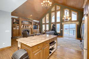 Kitchen featuring open floor plan, a chandelier, a fireplace, pendant lighting, and wooden ceiling