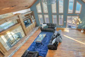 Living area featuring suspended lighting, wood finished floors, a fireplace, and a vaulted wooden ceiling
