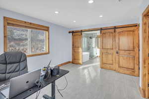 Office with recessed lighting and a barn door, looking into bathroom