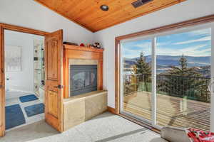 Carpeted living area with a mountain view, a fireplace, wooden ceiling, and recessed lighting
