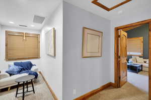 Hallway featuring light colored carpet and baseboards