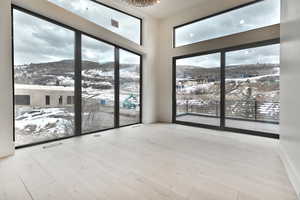 Primary suite featuring vaulted ceilings, expansive windows, light wood finished floors