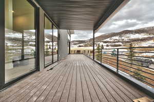 upper covered deck featuring a mountain view running length of the home