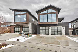 Modern mountain house featuring stone siding, an attached garage, and driveway