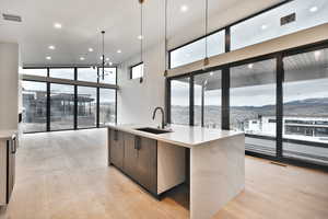 Kitchen with pendant lighting, a center island with sink, light stone counters, modern cabinets, and recessed lighting