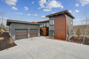 View of front facade with a garage, concrete driveway, an outdoor structure, and stone siding