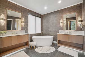 Bathroom featuring two vanities, a freestanding tub, recessed lighting, and tile walls