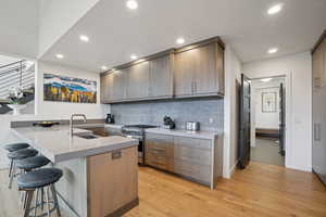 Kitchen featuring a peninsula, a kitchen bar, modern cabinets, appliances with stainless steel finishes, and decorative backsplash