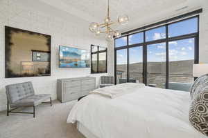 Carpeted bedroom featuring access to exterior, a chandelier, and tile walls