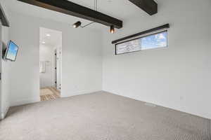 Unfurnished room with beam ceiling and light carpet