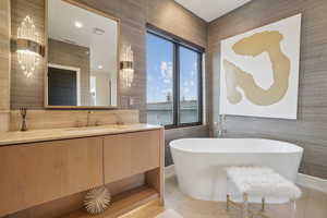 Full bath with light tile patterned floors, a freestanding bath, vanity, and wallpapered walls