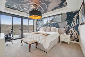 Carpeted bedroom featuring a tray ceiling, access to outside, and multiple windows