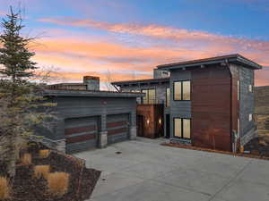 View of front facade featuring stone siding, driveway, and a garage