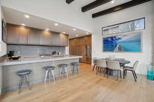 Kitchen featuring a breakfast bar, recessed lighting, a peninsula, brown cabinetry, and built in fridge