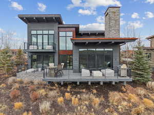 Rear view of property with a balcony, a wooden deck, and a chimney