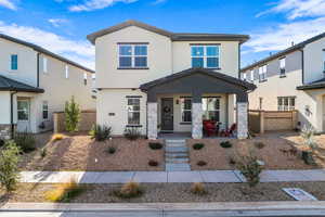 View of front of home with a porch, stucco siding, and stone siding