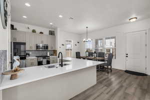 Kitchen with a peninsula, pendant lighting, appliances with stainless steel finishes, recessed lighting, and dark wood-style floors