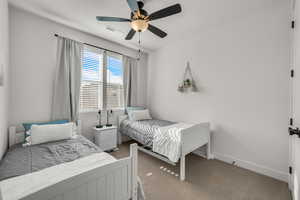Carpeted bedroom featuring a ceiling fan and baseboards