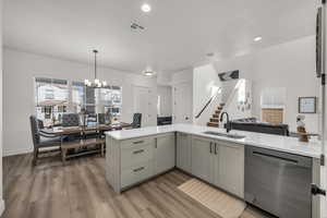 Kitchen featuring dishwasher, hanging light fixtures, light wood-style floors, open floor plan, and a chandelier