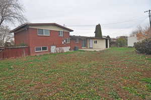 Rear view of house featuring a patio area, a fenced backyard, and brick siding