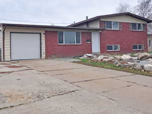 Tri-level home with brick siding, concrete driveway, and a garage