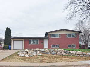 Tri-level home with brick siding, concrete driveway, and an attached garage