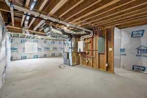 Unfinished below grade area with electric panel, tankless water heater, and heating unit