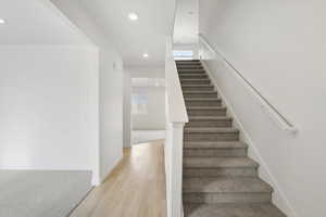 **DISCLAIMER** Interior colors & finishes may vary.Staircase with plenty of natural light, wood finished floors, recessed lighting, and carpet floors