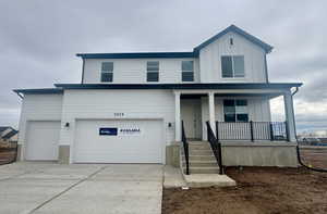 View of front of house featuring covered porch, concrete driveway, a garage, and board and batten siding
