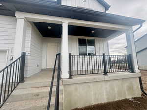 Doorway to property with board and batten siding and covered porch