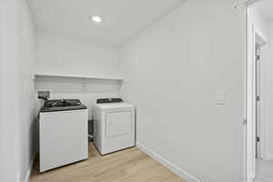 Laundry room featuring light wood-style floors and separate washer and dryer
