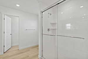 Bathroom with a shower stall, light wood-style flooring, and recessed lighting