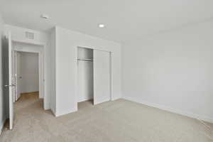 Unfurnished bedroom featuring light carpet, a closet, and recessed lighting