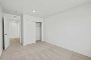 Unfurnished bedroom featuring light carpet and a closet