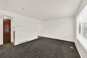 Spare room featuring dark colored carpet