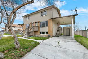 View of front facade with concrete driveway, brick siding, an attached carport, an outdoor structure, and stairway