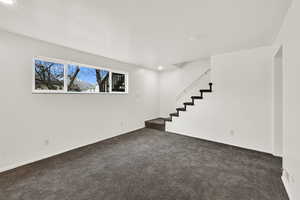 Below grade area with stairway, dark colored carpet, and recessed lighting