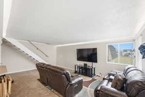 Living room with carpet, a textured ceiling, and stairs