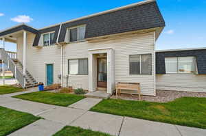 View of front of house featuring mansard roof, a shingled roof, a front yard, and stairway